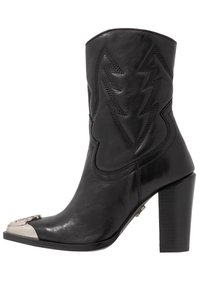 Černá kožená kotníková bota s vysokým blokovým podpatkem, dekorativním prošíváním ve tvaru blesku a kontrastním světlým špičkovým akcentem.