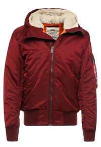 Herenbomberjack in bordeaux met een zachte nepbontkraag, ritssluiting, geribbelde manchetten en een oranje voering; heeft een mouwzak met tekst.