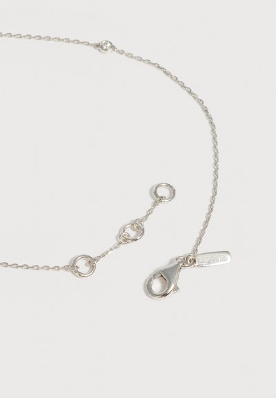 Collier chaîne en argent avec fermoir mousqueton et plusieurs maillons circulaires pour longueur ajustable sur fond blanc uni.