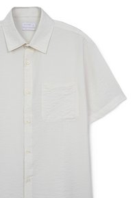 Camicia bianca a maniche corte realizzata in tessuto testurizzato, con chiusura frontale a bottoni, una singola tasca sul petto e un design rilassato.