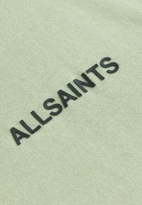 Minta zelena tkanina z mehko teksturo, ki prikazuje besedo "ALLSAINTS" v bold črni pisavi.