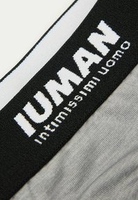 Zwarte elastische tailleband met witte "IUMAN" logo. De stof heeft een gladde textuur, met een grijze basis onder de tailleband.