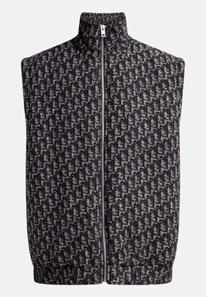 Gilet sans manches zippé en tissu à motifs bleu marine et crème, avec un col montant et un ourlet élastiqué pour une silhouette ajustée.