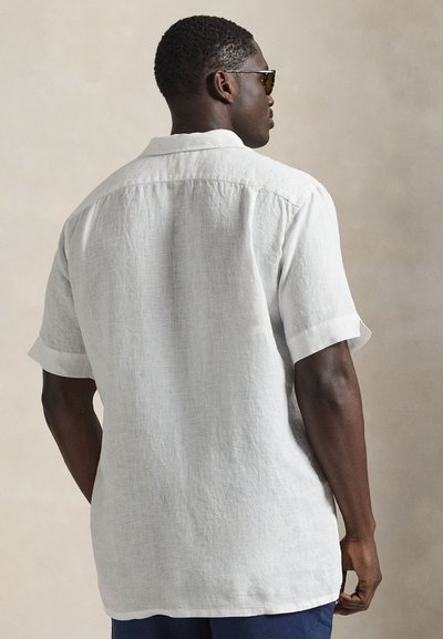 Vīriešu īsām piedurknēm krekls no balta lina, ar vaļēju piegriezumu, ar pogu aizdares apkakli un teksturētu apdari.
