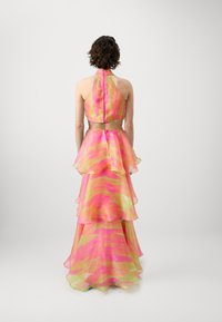 Stufenähnliches Kleid mit Halterneck-Design, gefertigt aus transparentem pink- und grünfarbenem Stoff mit wellenförmigen Mustern und sichtbaren Reißverschlüssen auf der Rückseite.