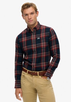 Marineblauw en rood geruit overhemd met lange mouwen, katoenen stof, met knoopsluiting aan de kraag, borstzak, gecombineerd met beige broek en een gevlochten bruine riem.