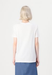 Camiseta de algodón blanca de manga corta y cuello redondo, con un ajuste holgado y sin etiqueta ni diseño visible en la parte posterior.