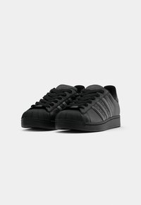 Black athletic shoes featuring a textured leather upper, round toe with rubber shell, six eyelets for laces, and three horizontal stripes.