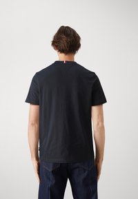 Camiseta de manga corta azul marino hecha de algodón suave. Presenta un diseño de cuello en V y una pequeña etiqueta tricolor en la parte posterior del cuello.