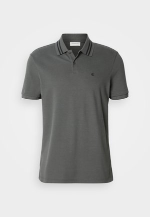 Grey polo shirt with a ribbed collar featuring navy stripes, short sleeves, and a small embroidered logo on the chest. Smooth texture.