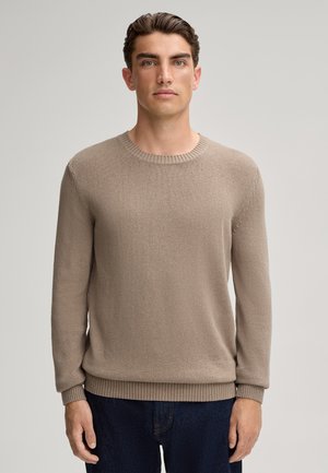 Beiger Strickpullover mit Rundhalsausschnitt, gerippten Bündchen und Saum, aus einem strukturierten Stoff gefertigt, kombiniert mit dunkelblauen Jeans.