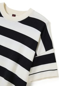 Maglione a righe bianche e nere realizzato in morbido tessuto a maglia, con collo a girocollo a costine e maniche corte ampie. Le righe alternano larghezze diverse.