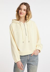 Jasnożółta bluza z kapturem z półsuwnym zapięciem z przodu, regulowanym kapturem i ściągaczami przy rękawach. Charakteryzuje się gładką teksturą i luźnym krojem.