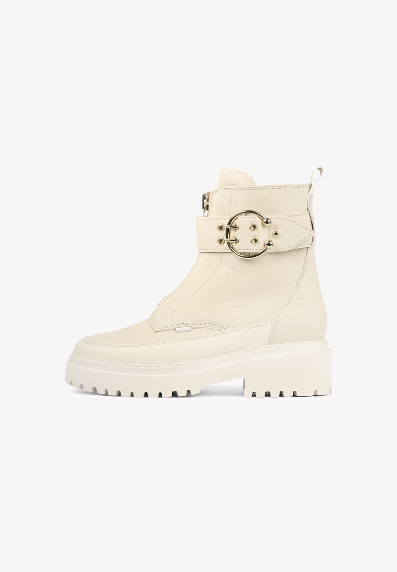 Bottine chunky en cuir blanc avec fermeture éclair sur le côté, large sangle et boucle métallique circulaire, surface texturée et semelle épaisse à motifs.
