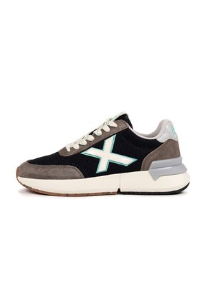 Chaussure de sport noire et grise avec une tige en mesh, des accents en daim, une semelle blanche et un logo vert menthe. Elle présente un tissu texturé et des lacets plats.