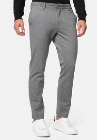 Pantalones grises a medida de tejido texturizado con frente plano, corte slim y dos bolsillos laterales, combinados con zapatillas blancas.