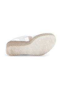 White sandal with crisscross straps, textured wedge heel, and patterned rubber sole. Features a natural cork accent on the base.