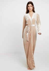 Robe lunga in velluto beige con una finitura simile alla seta. Presenta un design avvolgente, maniche lunghe e una cintura coordinata. Tessuto morbido e caduta elegante.