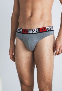 Γκρι βαμβακερά εσώρουχα με ζώνη μάρκας "DIESEL" σε μαύρο και κόκκινο χρώμα, που προσφέρουν σφιχτή εφαρμογή και απαλή υφή.