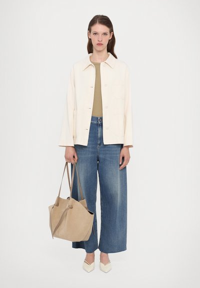 Light cream jacket, olive top, loose blue jeans, and beige bag; white pointed flats. The outfit features a casual, relaxed fit.