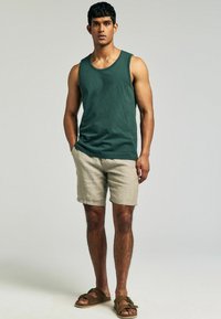 Grøn bomulds tanktop, beige linned shorts, brune sandaler. Enkel design med en afslappet pasform; glat tekstur, minimal detaljering.