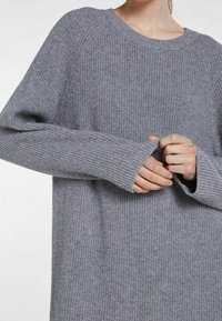 Maglione grigio lavorato a maglia con una texture a coste, scollatura rotonda e maniche lunghe. Presenta una vestibilità rilassata e un motivo di lavorazione a maglia distintivo su tutto il capo.