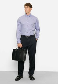 Long-sleeve purple checkered shirt with black buttons, paired with dark trousers and black leather shoes. Model holds a black briefcase.