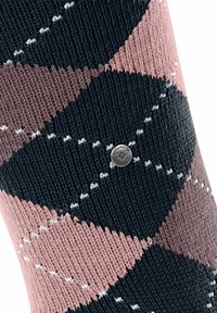 Primo piano di una calza con motivo, che presenta colori nero, rosa e bianco in un design a diamante, con un piccolo tag in metallo visibile.