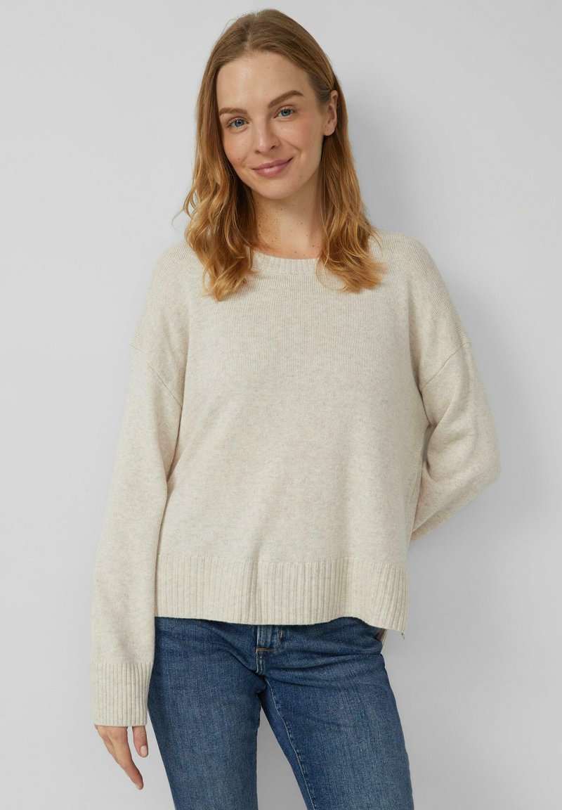 Hellbeiger Strickpullover mit lockerem Schnitt, gerippten Bündchen und Saum. Hergestellt aus weichem Stoff mit dezentem Muster. Kombiniert mit dunkler Jeans.