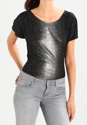 Body negro de manga corta con un patrón plateado brillante y un escote en forma de corazón, combinado con jeans grises. Tejido suave con un ligero brillo.
