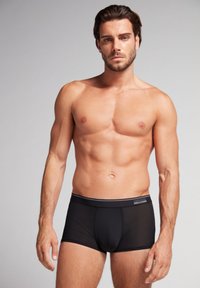 Svarta boxershorts i slät tyg, med en åtsittande design, bred elastisk midja och minimalistisk logotypdetalj.