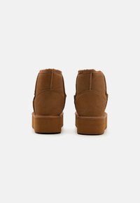 Pruunist suede'ist ümmarguse kujuga ankle'iboot'id, pehme fleece'iga voodriga ja lameda kummist tallaga. Omab õmmeldud õmblusi ja pehmendatud krae.