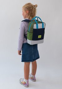 Färgglad barnryggsäck med paneler i grönt, marinblått, blått och grått. Inkluderar två sidofickor och en rektangulär form med dubbla handtag.