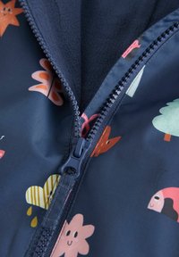 Reißverschlussjacke aus marineblauem, gemustertem Stoff mit bunten Illustrationen von Pflanzen und Tieren; weiche Fleece-Innenauskleidung.