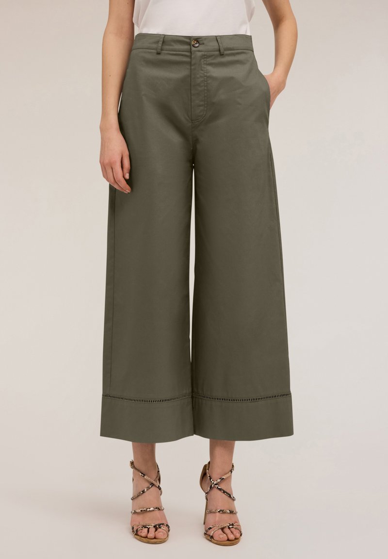 Wijdvallende, olijfgroene katoenen broeken met een hoge taille, zijzakken en decoratieve stiksels aan de onderkant. Gecombineerd met sleehakken.