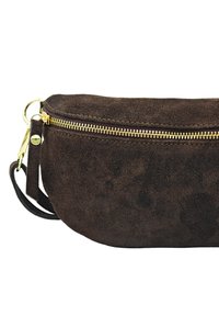 Pochette en suede marron avec une forme courbée, fermeture éclair dorée et une bandoulière. Texture douce avec un design minimaliste et sans motifs visibles.