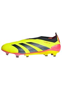 Crampons de football jaune vif avec des rayures noires et grises, une surface texturée et un accent rouge sur le talon ; conçus pour le sol ferme.