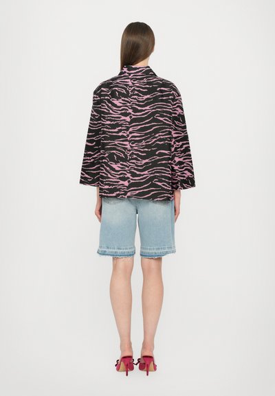 Must värviline zebra triibuline jope, suures mõõdus ja laiad varrukad. Kandmisest teksashortside ja fuksia värvi kontsadega, näidates casual välimust.