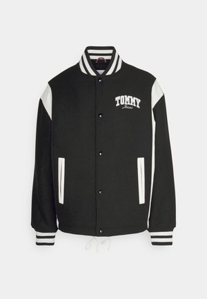 Sort og hvid varsity-jakke med stribet krave og manchetter, knaplukning, to lommer med hvid kant og "Tommy Jeans" logo på brystet.