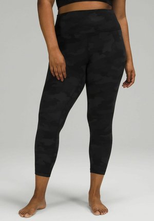 Black camo-patterned leggings with a high waistband, smooth texture, stretchy material, and cropped length, designed for comfort and flexibility.