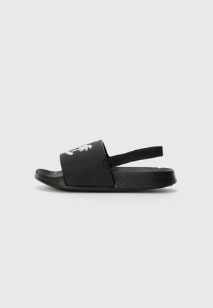 Čierne šľapky s rovnou podrážkou, textúrovaným popruhom a malým logom. Vyrobené z gumy pre trvácnosť a pohodlie.