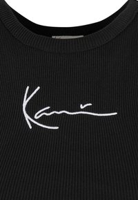 Must mustriba kangas topp, millel on valge tikitud signatuuridetail. Kõrgem kaelus ja tihe koe.