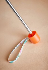 Metallist post heleroosa kummist alusega, mille külge on kinnitatud lillemustrilise kangast rihm haarde ja toe jaoks.