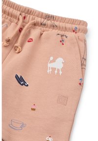 Pantalones cortos de sudadera color durazno con cintura elástica, que presentan estampados multicolores de un león, la Torre Eiffel, labios y otros motivos.