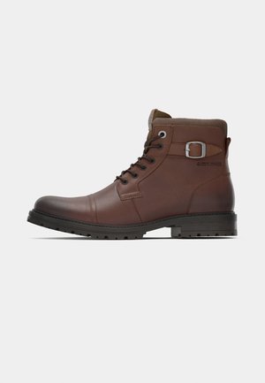 Brown leather lace-up ankle boot with buckle strap and sturdy black sole, side view on white background.
