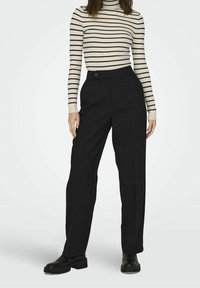 Pantalon noir taille haute à coupe droite, avec une fermeture à un bouton et des poches latérales, associé à un col roulé rayé.