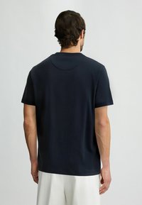 Námorně modré tričko s krátkým rukávem a kulatým výstřihem, s hedvábně hladkým povrchem. Jednoduchý design bez viditelných vzorů nebo akcentů.