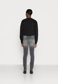 Svart kort hoodie i kombination med grå gradient skinny jeans, med en slät yta och subtila detaljer på fickorna.