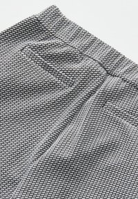 Black and white patterned fabric with a textured weave, featuring a slight stretch and an elastic waistband for comfort.