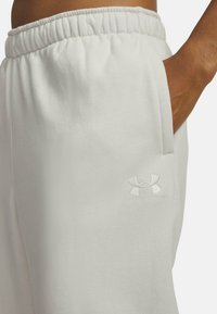 Svetlo šedé tepláky vyrobené z mäkkej tkaniny, s elastickým pásom a bočnou vreckom. Logo Under Armour je diskrétne vyšívané.